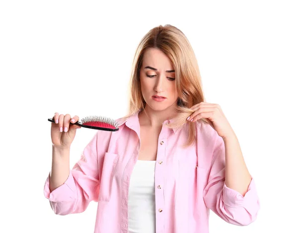 Mujer joven cepillando el cabello contra fondo blanco — Foto de Stock