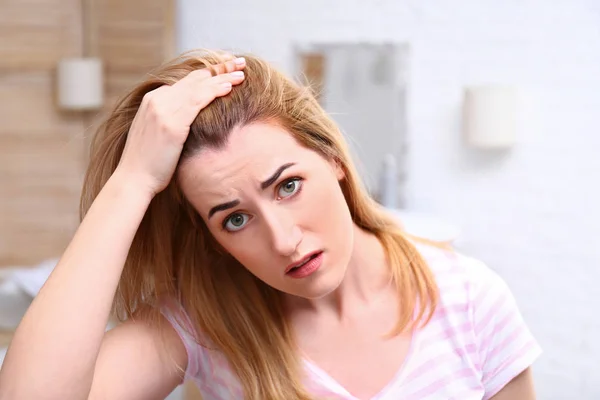 Emotional woman with hair loss problem in bathroom