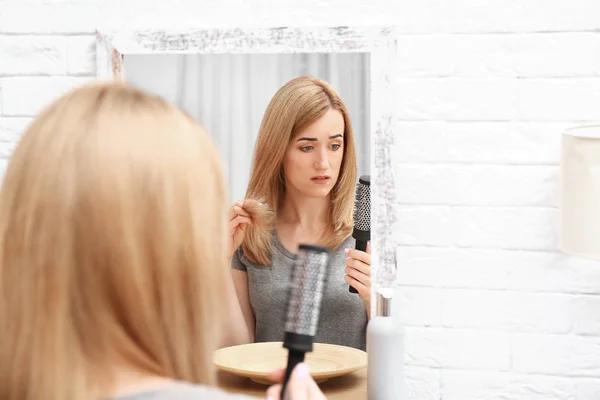 Emotional woman brushing hair near mirror in bathroom — Stock Photo, Image
