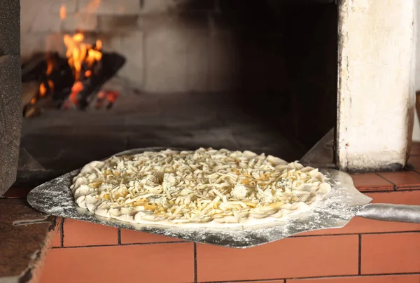 Sätta pizza i ugnen i restaurangkök — Stockfoto