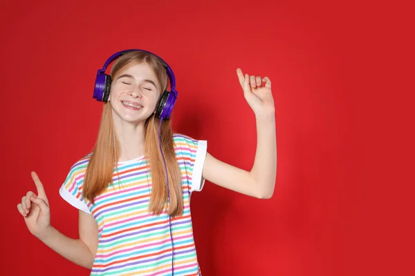 色の背景にヘッドフォンで音楽を楽しむ十代の女の子。テキスト用のスペース — ストック写真