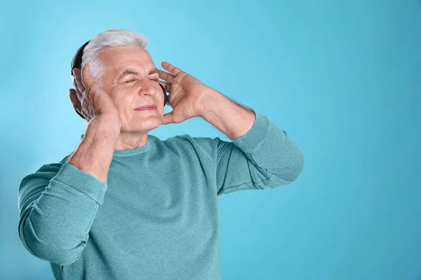 Homem maduro desfrutando de música em fones de ouvido no fundo de cor. Espaço para texto — Fotografia de Stock