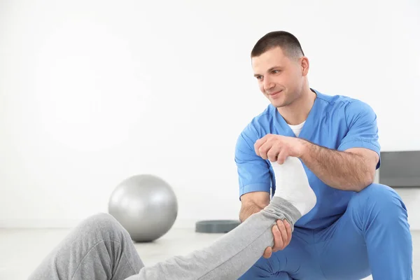 Professionele fysiotherapeut werken met mannelijke patiënt in revalidatiecentrum. Ruimte voor tekst — Stockfoto