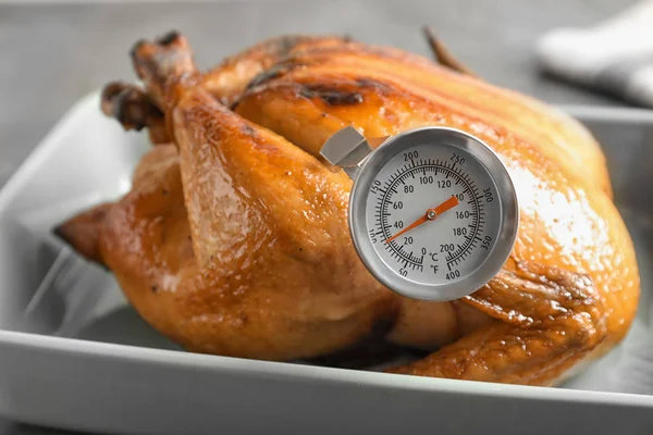 Roasted turkey with meat thermometer in baking dish