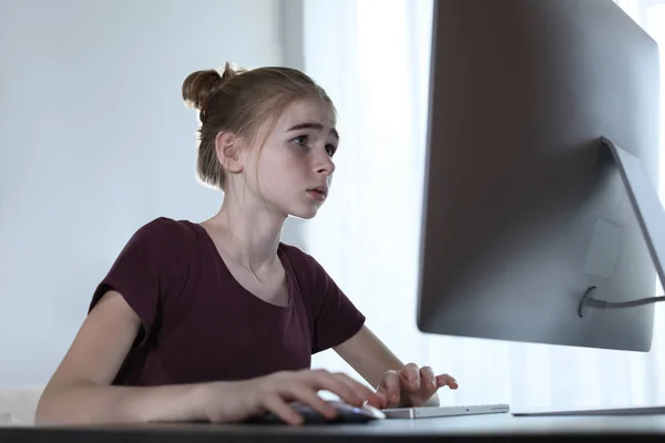 Расстроенная девушка-подросток за компьютером в помещении. Опасность интернета — стоковое фото