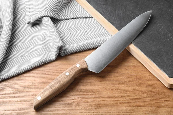 Composición con cuchillo de chef afilado y tabla sobre fondo de madera — Foto de Stock