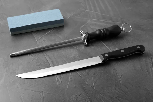 Нож и различные точилки на сером фоне — стоковое фото