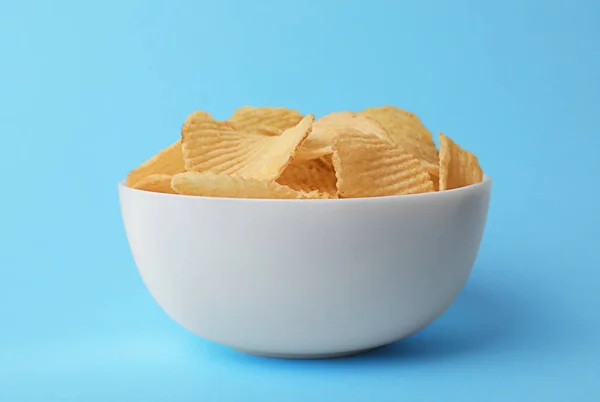 Heerlijke knapperige aardappelchips in schaal op kleur achtergrond — Stockfoto