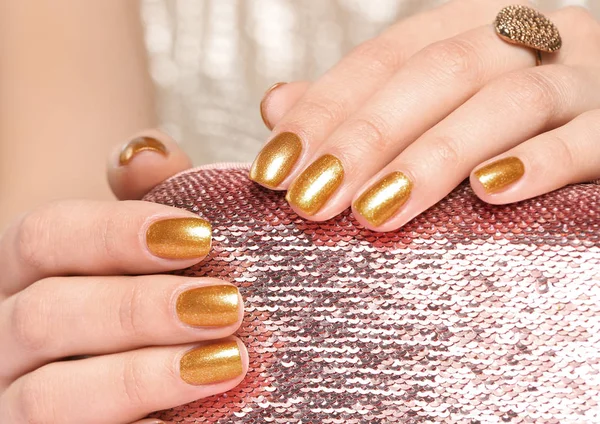 Kobieta trzymająca wypielęgnowane ręce złotym lakierem do paznokci na torbie, zbliżenie — Zdjęcie stockowe