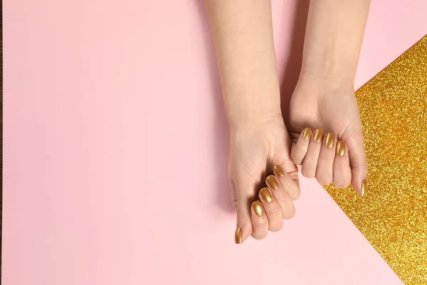 Mujer mostrando las manos cuidadas con esmalte de uñas de oro en el fondo de color, vista superior. Espacio para texto — Foto de Stock