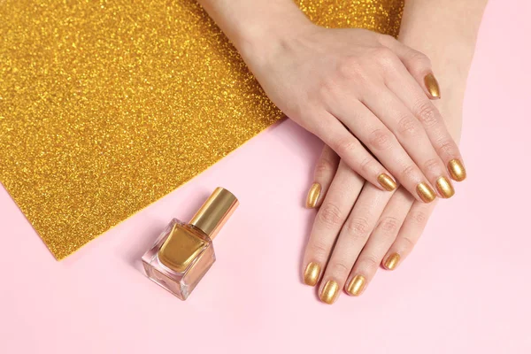 Kobieta pokazuje manicure ręce ze złotym lakierem do paznokci na tle koloru, zbliżenie — Zdjęcie stockowe