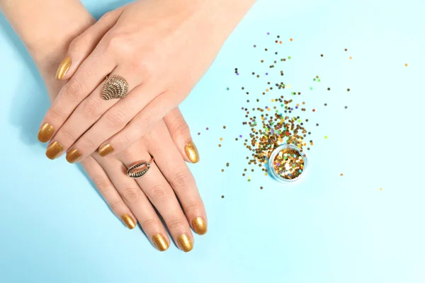 Γυναίκα δείχνει περιποιημένα χέρια με χρυσό βερνίκι νυχιών και glitter στο φόντο χρώμα, πάνω όψη — Φωτογραφία Αρχείου