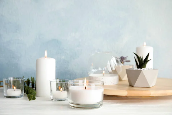 Burning aromatic candle and plants on table. Space for text