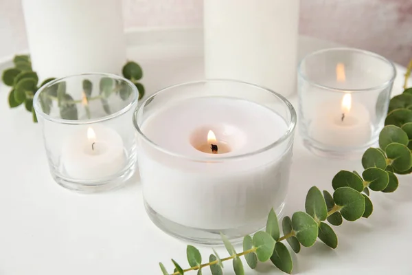 Kompozycja z płonących świec aromatycznych i eukaliptusa na stole — Zdjęcie stockowe