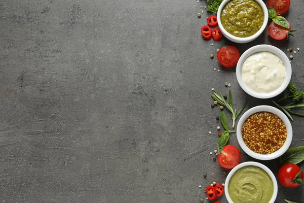 Cuencos con diferentes salsas e ingredientes sobre fondo gris, la puesta plana. Espacio para texto — Foto de Stock