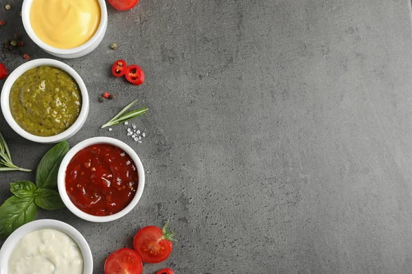 Schalen met verschillende sauzen en ingrediënten op grijze achtergrond, plat gelegd. Ruimte voor tekst — Stockfoto