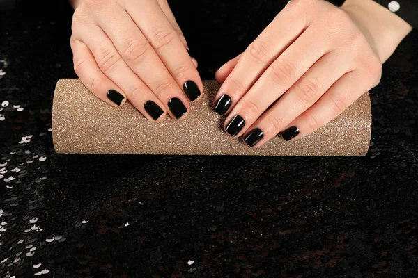 Woman showing black manicure on rolled shiny paper, closeup with space for text. Nail polish trends — Stok fotoğraf