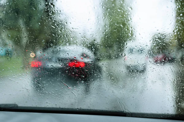 Blurred view of road through wet car window. Rainy weather — Stock Photo, Image
