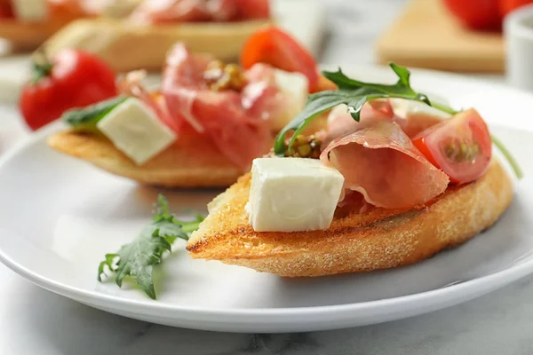 Placa de sabrosos bruschettas con jamón en la mesa, primer plano —  Fotos de Stock