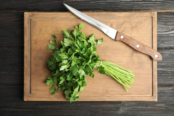Board with fresh green parsley and knife on wooden background, top view — Stock Photo, Image
