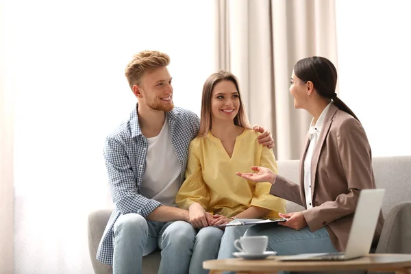 Agente de seguros femenino que trabaja con parejas jóvenes en el cargo — Foto de Stock