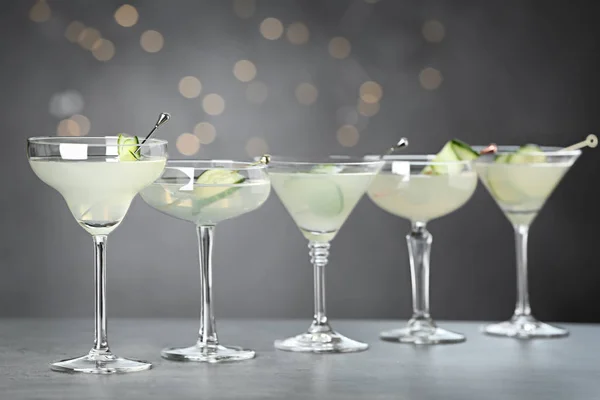 Sklenice Martini s okurkami na šedém stole proti rozmazaných světlech — Stock fotografie