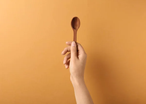 Vrouw met lege houten lepel op kleur achtergrond, close-up. Ruimte voor tekst — Stockfoto