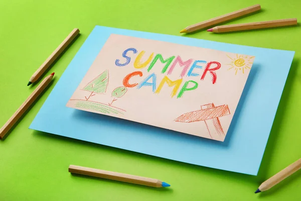 Папір з написаним текстом SUMMER CAMP, малюнки та різні олівці на кольоровому фоні — стокове фото