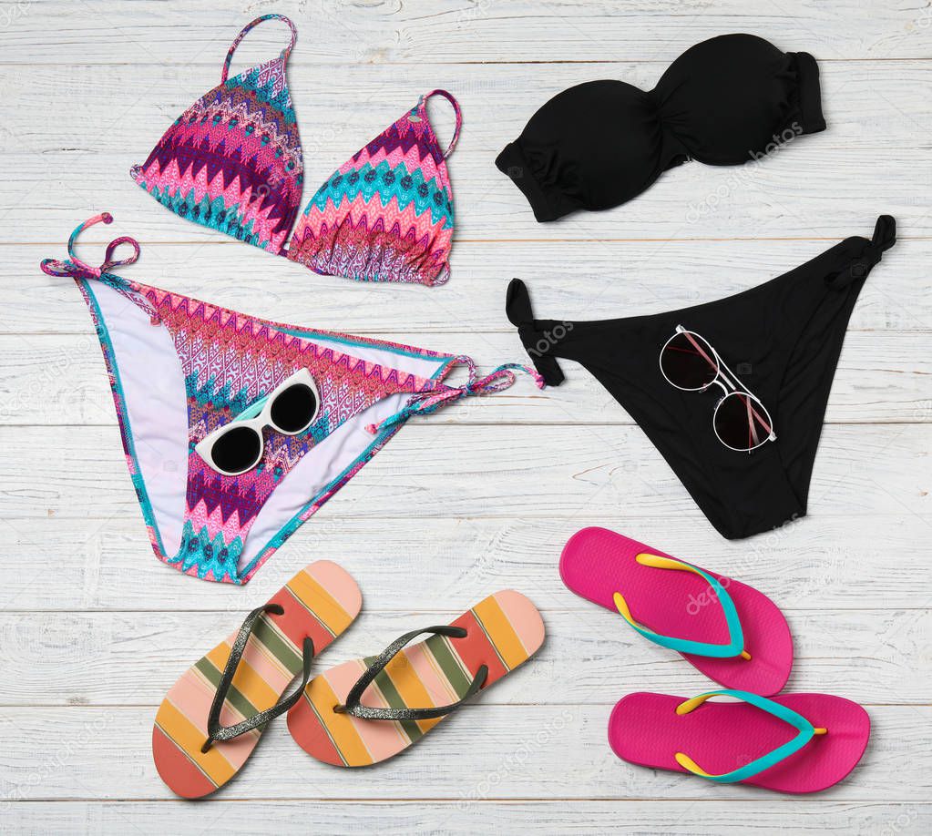 Flat lay composition with swimsuits and beach accessories on wooden background