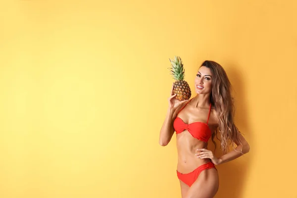 Pretty sexy woman in stylish bikini with pineapple on color background, space for text — Stock Photo, Image