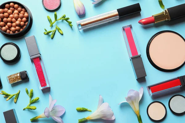 Different makeup products and flowers on color background, flat lay with space for text