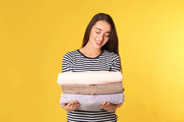 Mujer joven feliz sosteniendo ropa limpia en el fondo de color —  Fotos de Stock