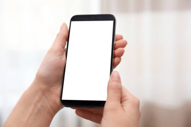 Bulanık arka planda boş ekran ile akıllı telefon tutan kadın, eller closeup. Metin alanı
