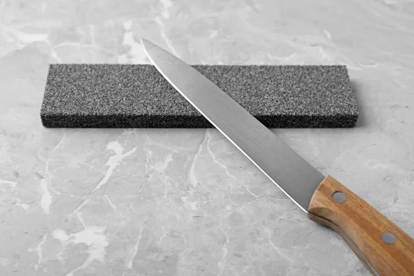 Нож и заточка камня на сером фоне — стоковое фото