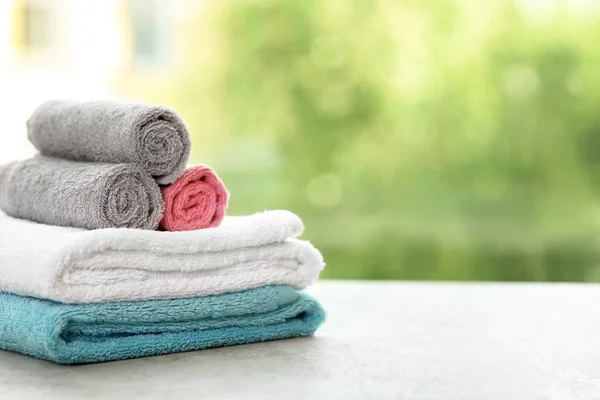Pila di asciugamani puliti sul tavolo su sfondo sfocato. Spazio per testo — Foto Stock