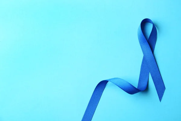 Niebieska wstążka na kolorowym tle, widok z góry z miejscem na tekst. Koncepcja świadomości raka jelita grubego — Zdjęcie stockowe
