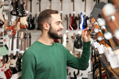 Alıcı modern müzik mağazasında gitar seçimi