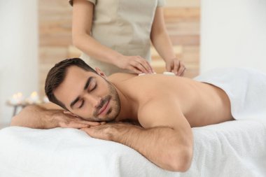 Yakışıklı adam spa salonunda sıcak taş masajı alan