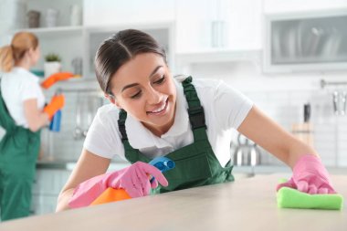 Mutfakta meslektaşım ile temizleme masası için bez ve püskürtücü kullanan kadın