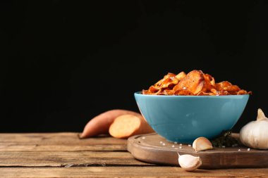 Siyah arka plana karşı masada tatlı patates cips ve sarımsak ile kompozisyon. Metin alanı
