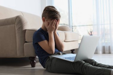 Odada laptop olan korkmuş küçük bir çocuk. İnternet tehlikesi