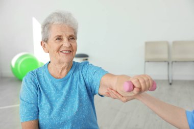 Rehabilitasyon merkezinde yaşlı hasta ile çalışan profesyonel fizyoterapist