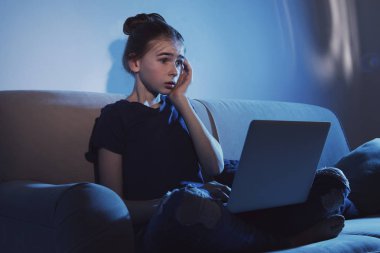 Karanlık odada kanepede laptop ile şok genç kız. İnternet tehlikesi
