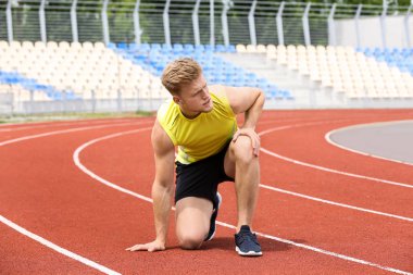 Stadyumda diz ağrısı çeken spor giyimli adam