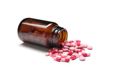 Beyaz arka planda vitamin hapları ve kapsülleri olan şişe.