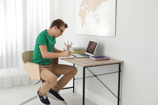 Adolescente menino fazendo sua lição de casa na mesa dentro de casa — Fotografia de Stock