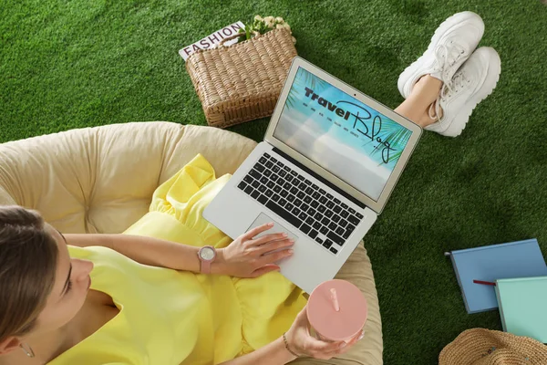 Frau hält Laptop mit offenen Reise-Blogger-Website auf Kunstrasen, über Ansicht — Stockfoto