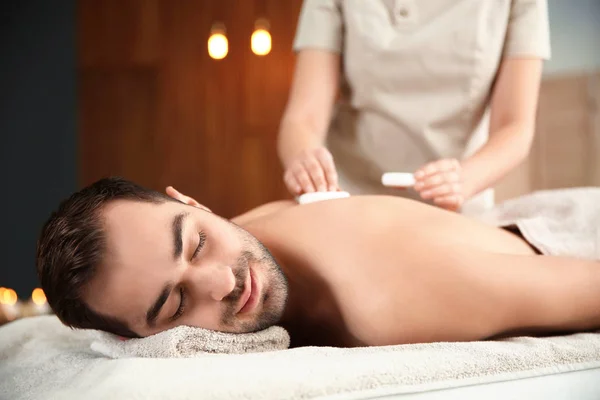 Красивий чоловік отримує масаж гарячим каменем у спа-салоні — стокове фото