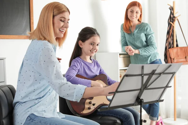 小女孩和她的老师和母亲在上音乐课。学习笔记 — 图库照片
