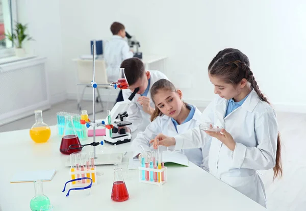 Alumnos inteligentes haciendo experimentos en la mesa en clase de química —  Fotos de Stock